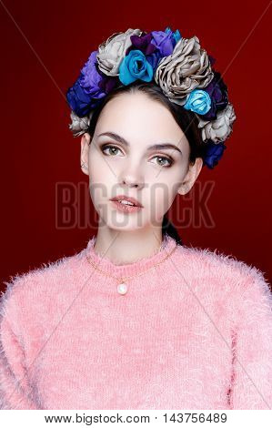 Beautiful model with a wreath of flowers on her head on red background