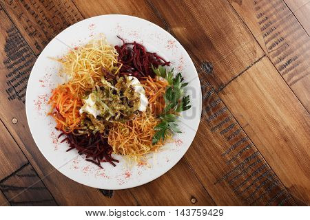 Chafan (Azerbaijan kitchen), mix from potato, carrot, beet, greens on white plate. wooden background