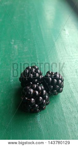three blackberries on green background,  several blackberries,  fresh berries