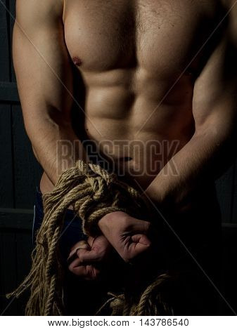 Sport. Young man with muscular body tied with rope