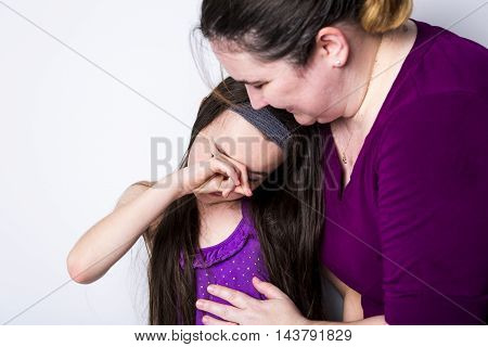 A mother comforting her daughter in studio white background