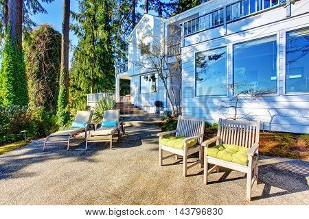 Backyard Patio Area With Chairs, Concrete Walkway And Landscaping Desing.