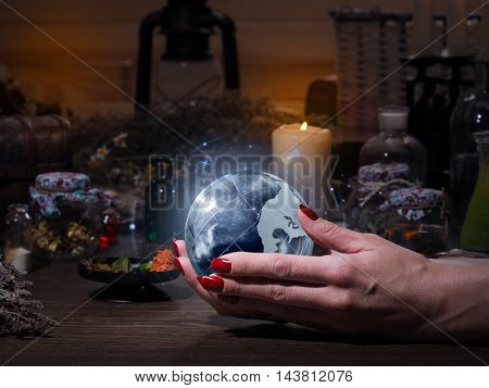 Women's hands holding the magic sphere with the stars. The blue glow. Flasks retort for alchemy. Concept - the world of astrology stars prediction occult spirituality spiritualism