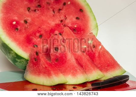 Ripe juicy watermelon and a few slices of watermelon on a light background. Healthy eating.