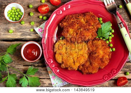 Cutlet with a crispy crust tomatoes and peas on a wooden background