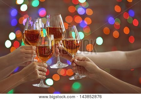 Female hands clinking glases with white wine on bokeh background