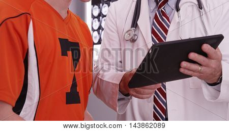 Portrait Of Medical Doctor Looking At Tablet Computer With College Athlete