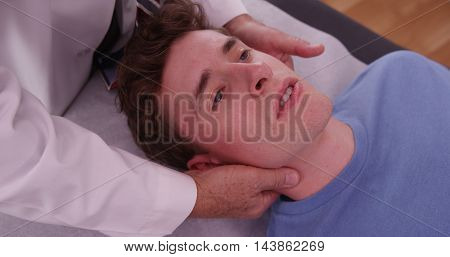 Young Adult Male With Chiropractor Examining Neck Pain