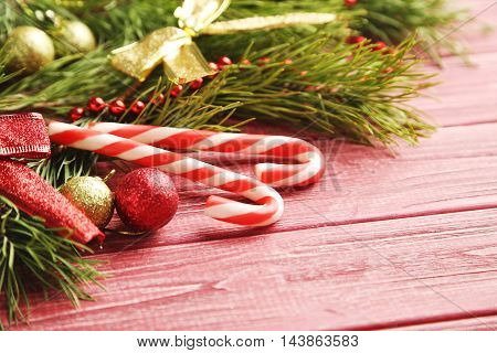 Christmax Tree Branch With Baubles, Candies On Red Wooden Table