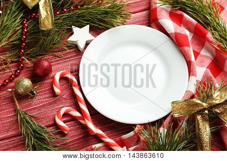 Christmax Tree Branch With Baubles, Candies On Red Wooden Table
