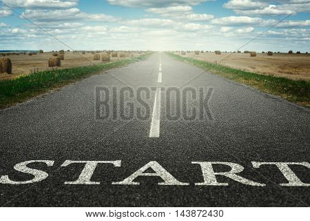The road stretches into the distance with the inscription start. On the horizon glow.