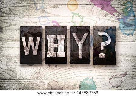 The word "WHY" written in vintage dirty metal letterpress type on a whitewashed wooden background with ink and paint stains.
