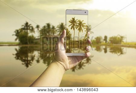 Hand taking photo of the fish village landscape by smartphone