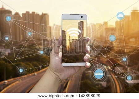 Hand holding white phone with city scape and wifi network connection concept