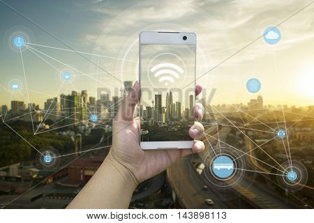 Hand holding white phone with city scape and wifi network connection concept