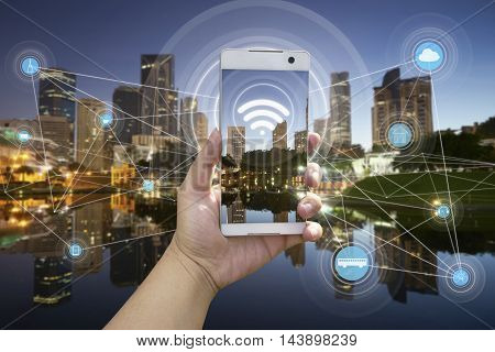 Hand holding white phone with city scape and wifi network connection concept .