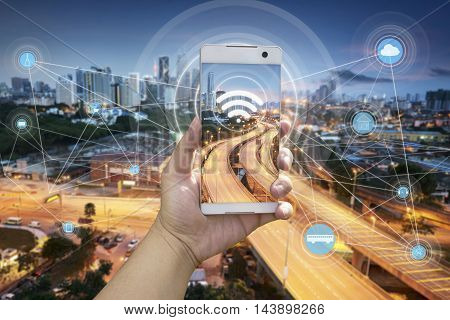 Hand holding white phone with city scape and wifi network connection concept .