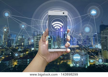 Hand holding white phone with city scape and wifi network connection concept .