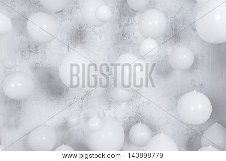 Wgite party balloons infronrt of gray texture wall