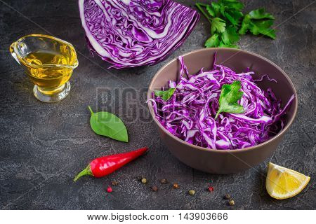 Purple cabbage salad and ingredients on a dark background.