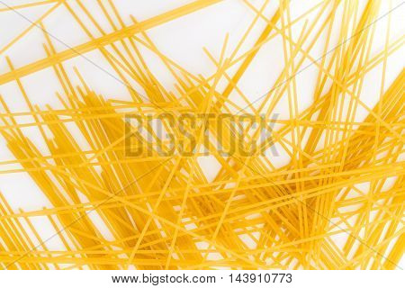 Spaghetti background. Yellow long spaghetti on white background. Thin pasta arranged in rows. Yellow italian pasta. Long spaghetti.