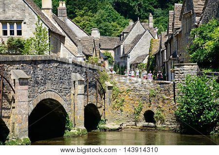 CASTLE COMBE, UNITED KINGDOM - JULY 20, 2016 - Stone bridge over the river Bybrook with cottages to the rear Castle Combe Wiltshire England UK Western Europe, July 20, 2016.