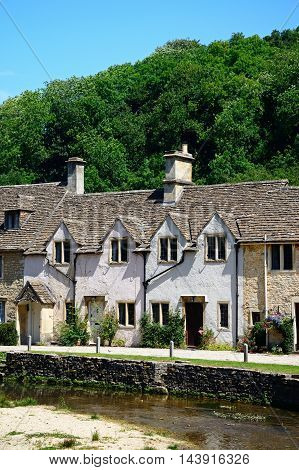 Stone cottages alongside the river Bybrook Castle Combe Wiltshire England UK Western Europe.