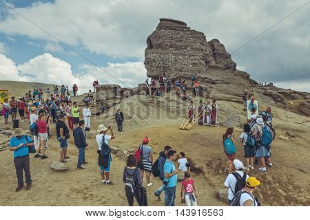 Bucegi Mountains Romania - August 6 2016: Tourists enjoy the performance of four Romanian women in colorful traditional costumes playing the tulnic near the Sphinx megalith in Bucegi mountains.