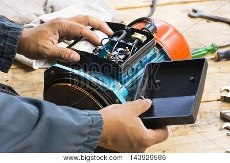 Electric motor  and man working equipment repair on wooden floor background.Background mechanic or equipment. Zoom in