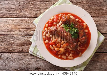 Grilled Sausage With Beans In Tomato Sauce On A Plate Close-up. Horizontal Top View