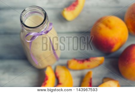 Peaches and smoothie on white wooden background