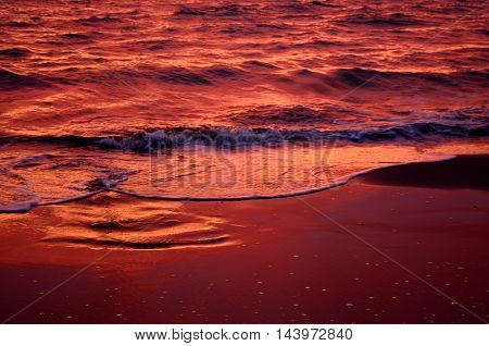Sea waves during a colorful sunset over a beautiful and romantic beach