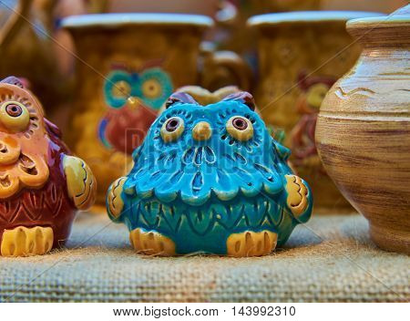 Blue owl - pottery handmade from clay glazed in natural sunlight against a background of other ceramic products
