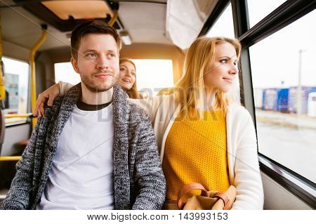Beautiful young couple traveling by bus looking out of window having fun in town.