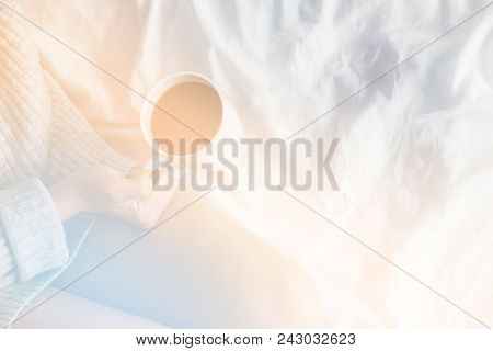 Girl In Bed Wearing Wool Sweater Holding Cup Of Coffee