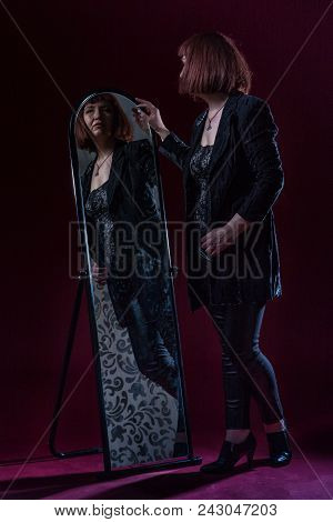 Confident Ugly Woman Wearing Black Suit Stands Near Mirrow In Front Of Camera On Stage With Crimson 