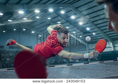 The Table Tennis Player In Motion. Fit Young Sports Man Tennis-player In Play On Sport Arena Backgro
