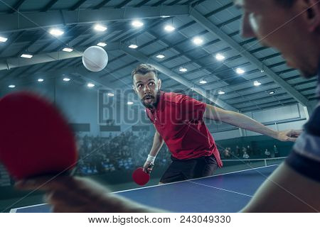 The Table Tennis Player In Motion. Fit Young Sports Man Tennis-player In Play On Sport Arena Backgro