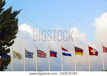 Flags Of Different Countries Flapping In Wind Against Blue Sky