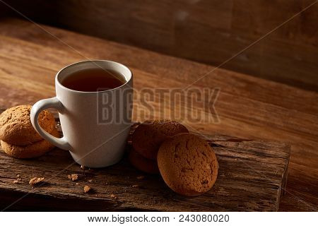 White Porcelain Mug Of Black Tea Or Earl Grey And Pile Of Sweet Cookies On Flat Piece Of Wood Over R