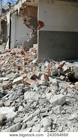 Damaged Building With Broken Walls And Many Bricks On The Ground