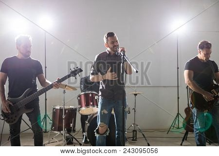 Lead Singer With Musicians Performing Rock And Roll Music On Stage