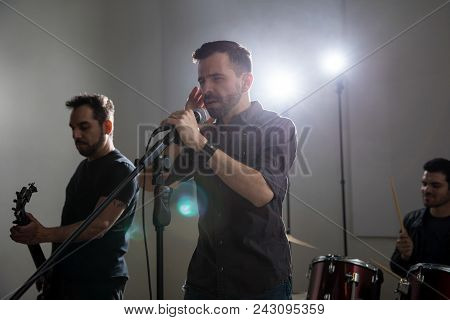 Lead Singer With Microphone And Rock And Roll Band Performing Live In Concert