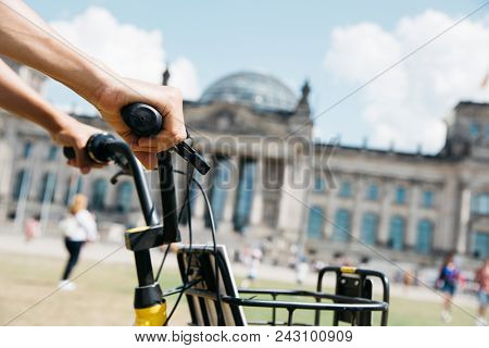closeup of a young caucasian man riding a bike by the Platz der Republik square, in Berlin, Germany, with the Reichstag building in the background