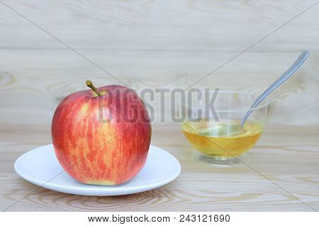 A Red And Yellow Apple On A White Plate And Honey In A Croissant With A Spoon On A Wooden Background