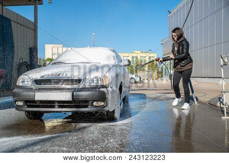 Young Woman Washing Car At Self-service Carwash
