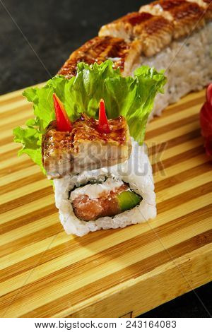 Kanada sushi rolls with salmon, eel, Philadelphia cheese, avocado and cucumber served on wood dish. Asian menu