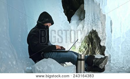 Hacker Hacks The Server. Man To Program On Laptop In Ice Cave. Around The Mysterious Ice Grotto. Man