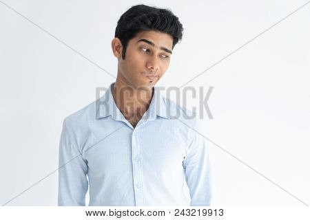 Grinning Pensive Indian Guy Sneakily Looking Aside. Young Liar Confused With Explanations. Portrait 