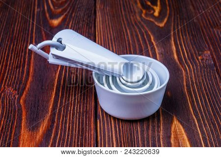 Measuring Set Table Spoons And Cups Plastic White Color On A Wooden Background. Devices, Measuring I